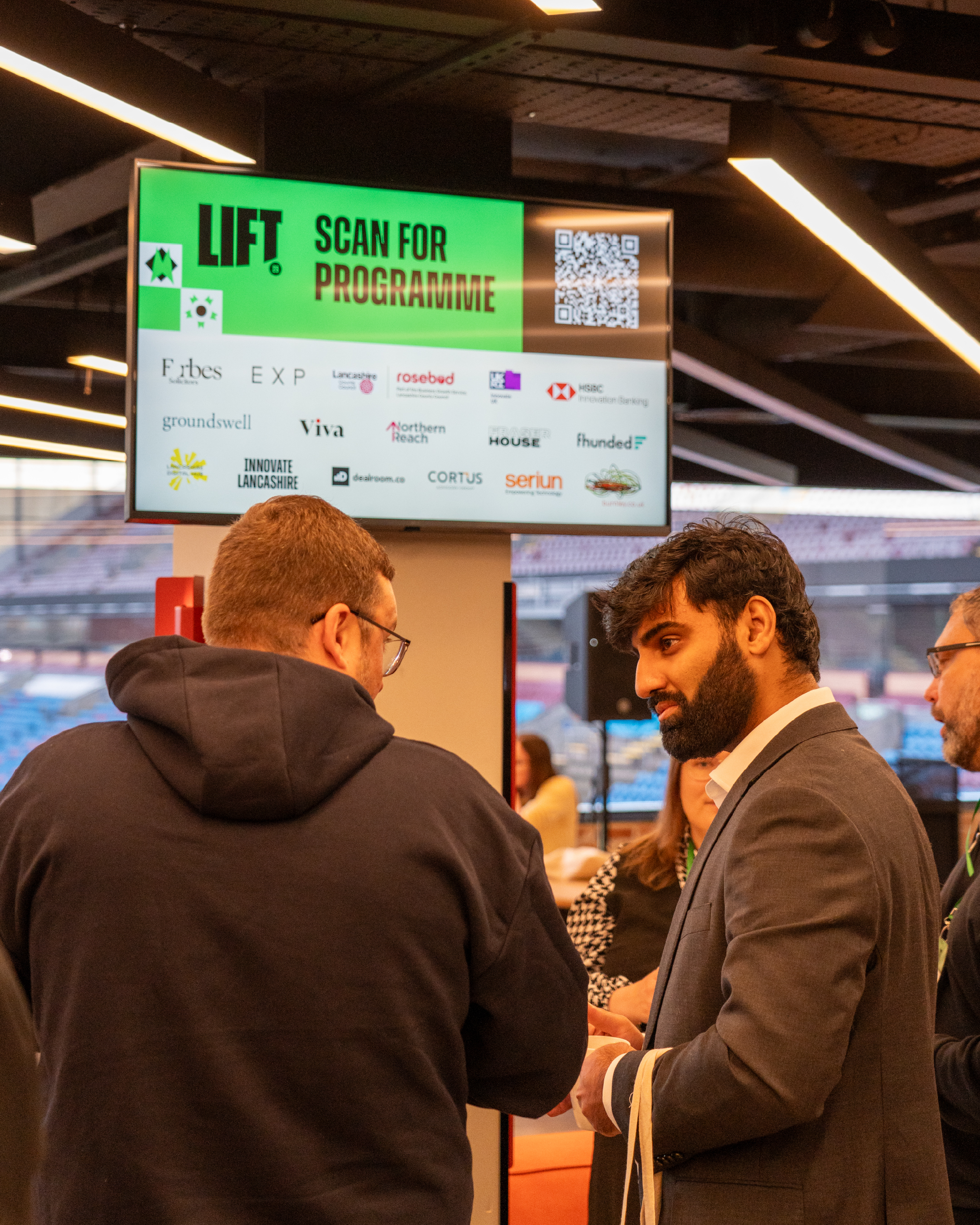 Attendees tslk in front of a screen displaying the QR code for the Digital Programme.