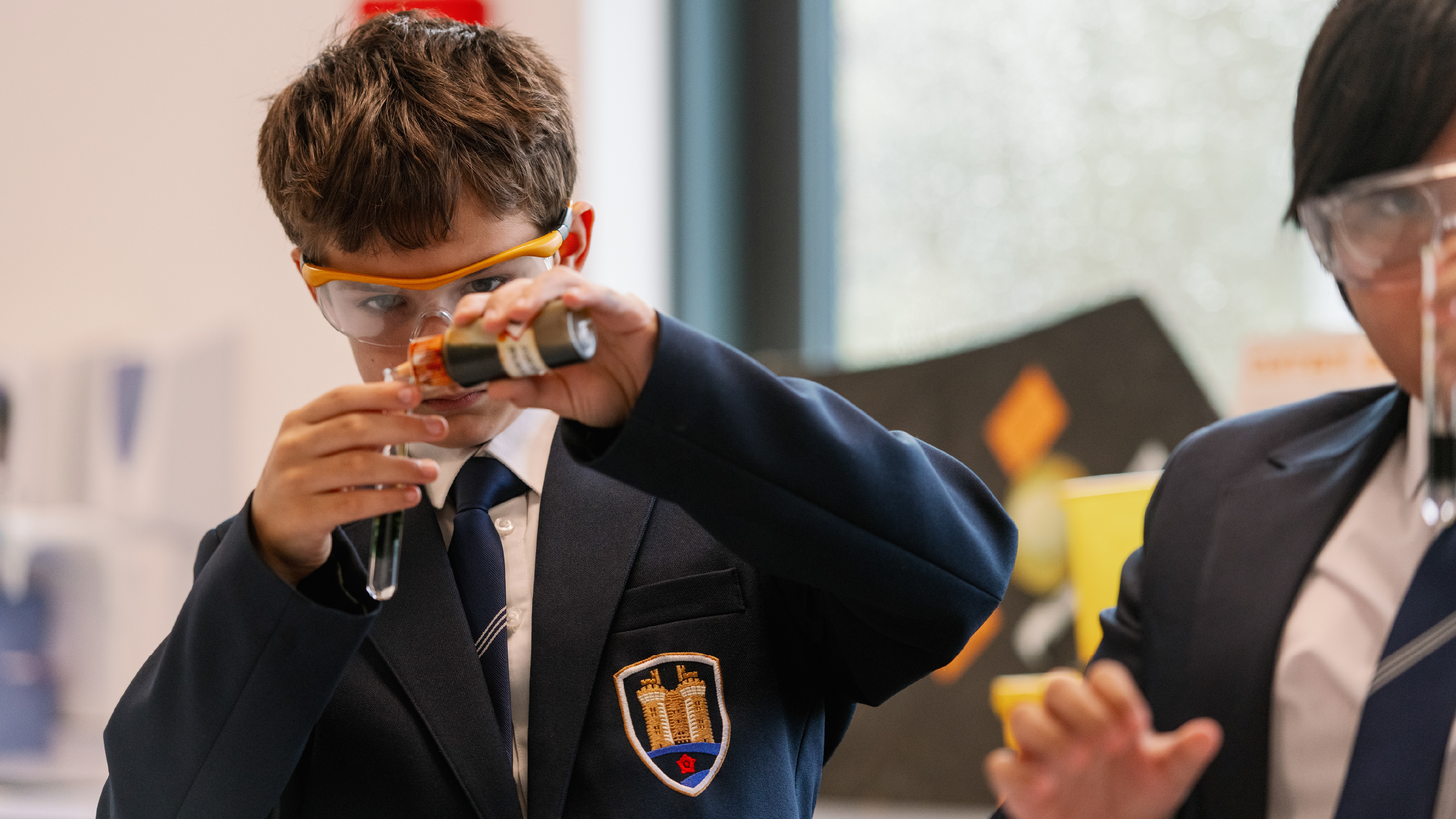 A schoolchild pours the contents of one test tube into another in a science lab.