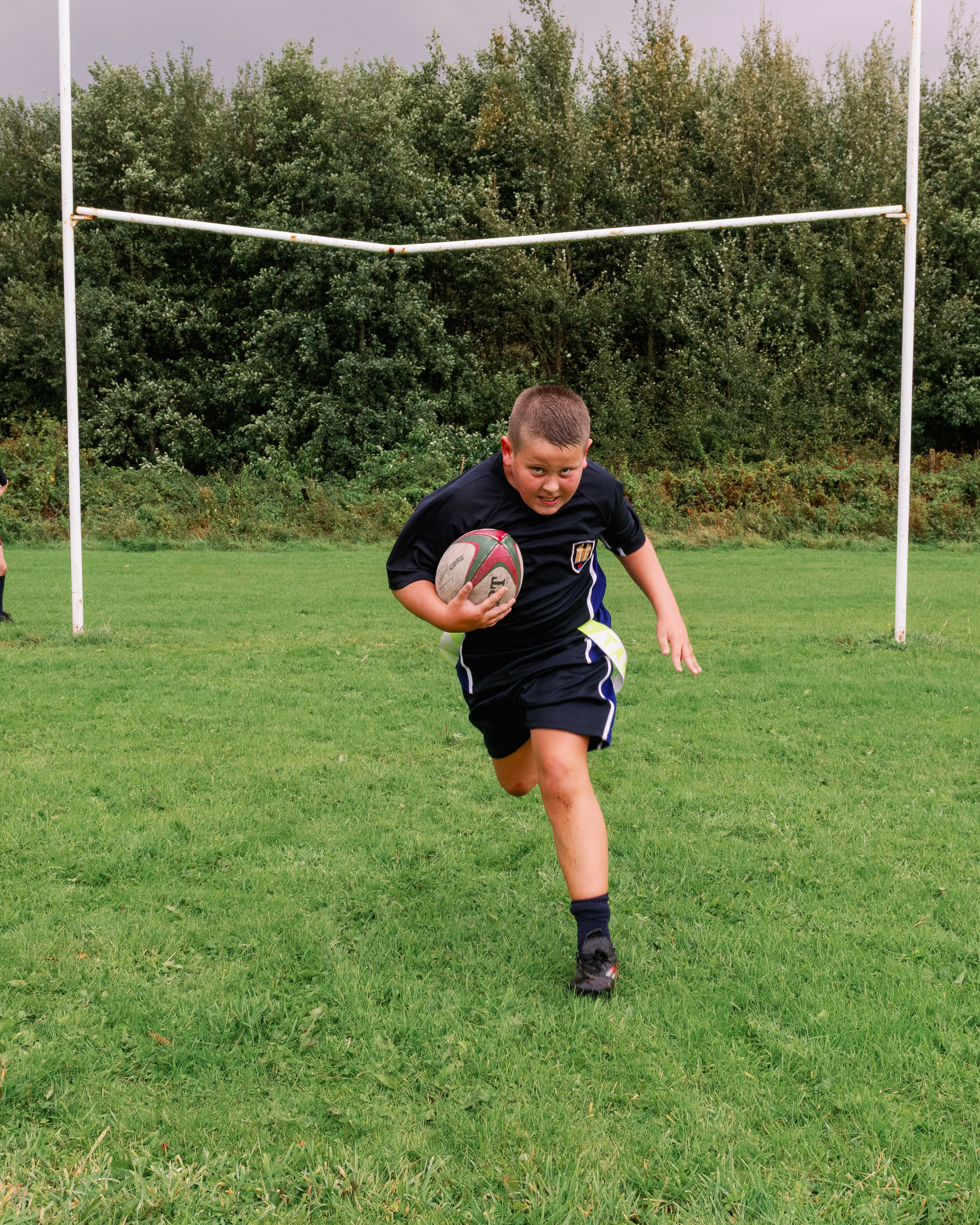 A school child runs towards the camera on a rugby pitch