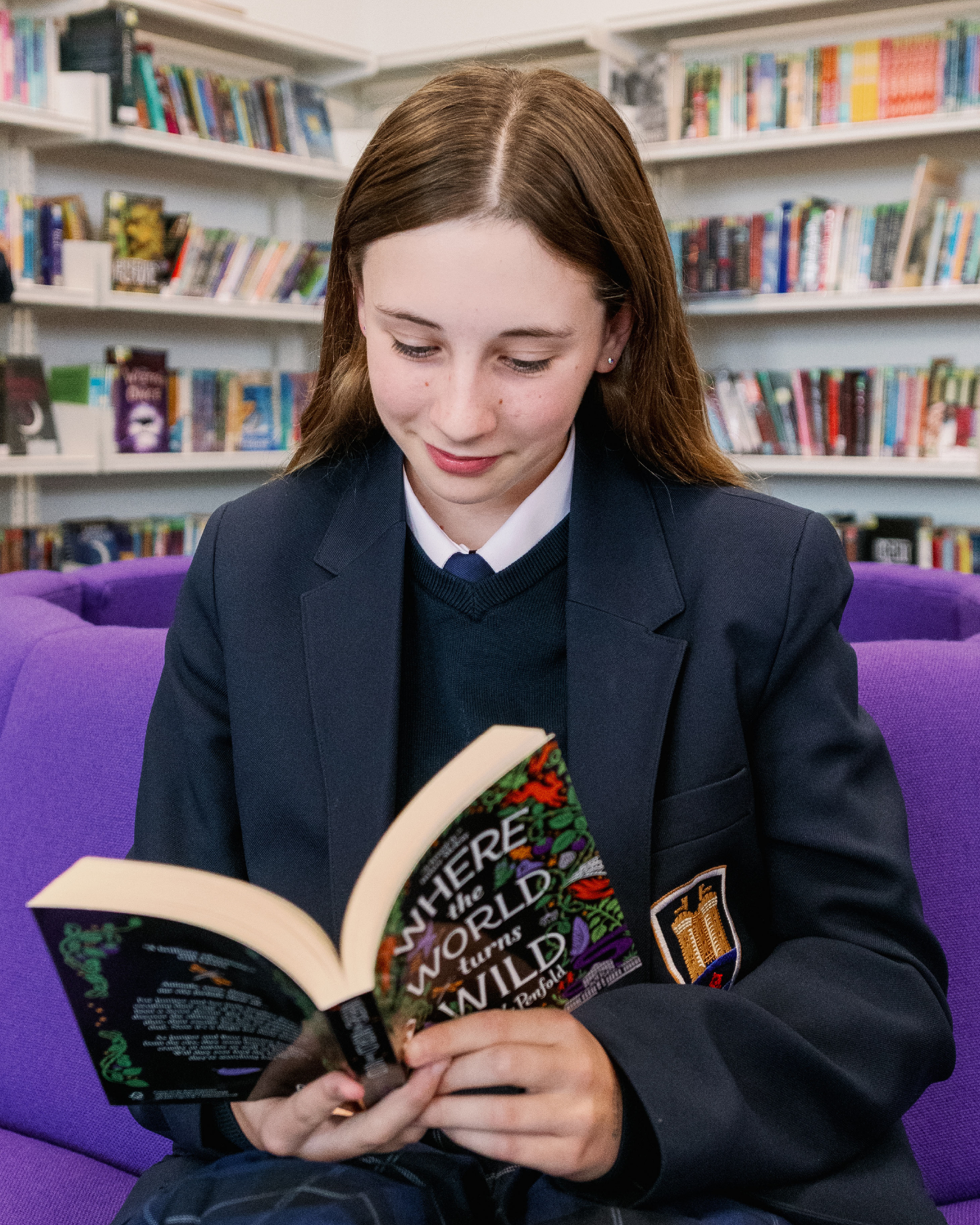 A child reads in a library, wearing the branded Lancaster High School uniform